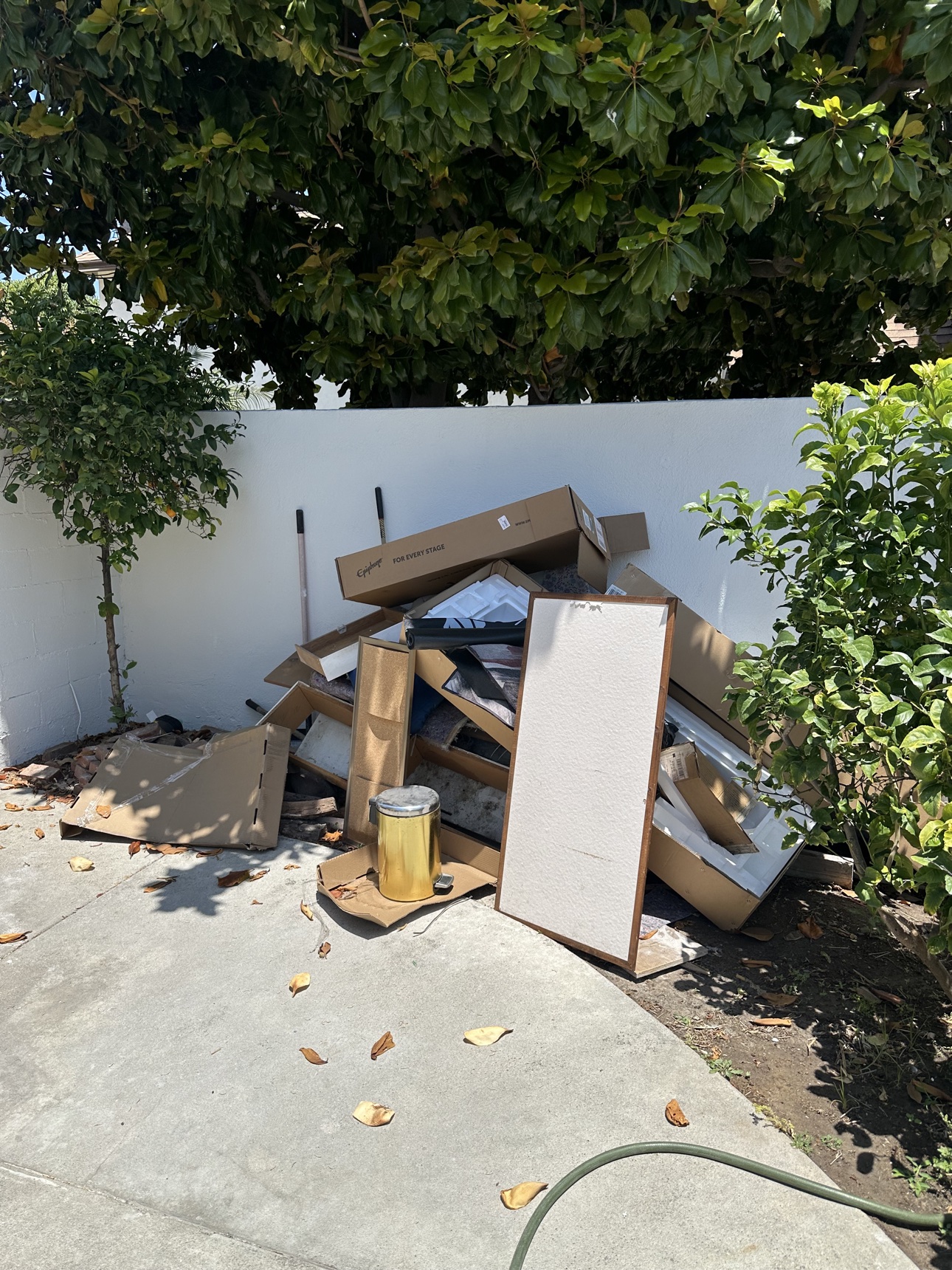 Discarded boxes, wood and household materials piled beside a wall before Delta’s Mission Viejo clean-out